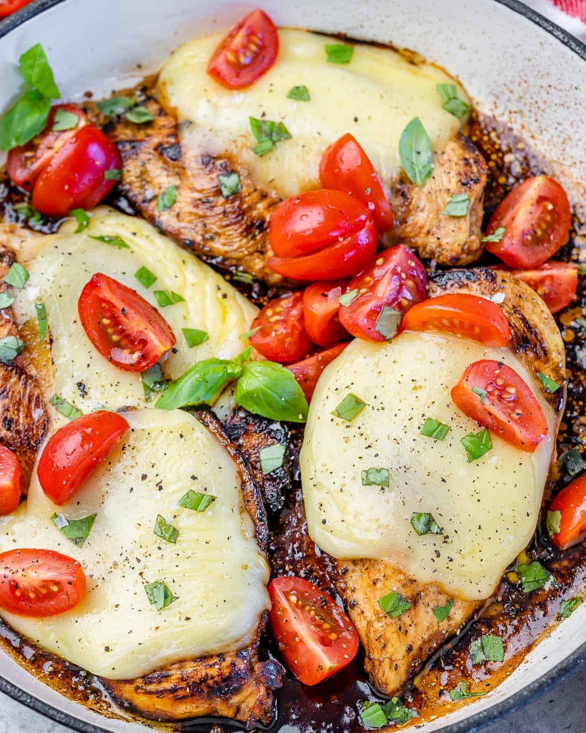 close up chicken caprese in a white skillet