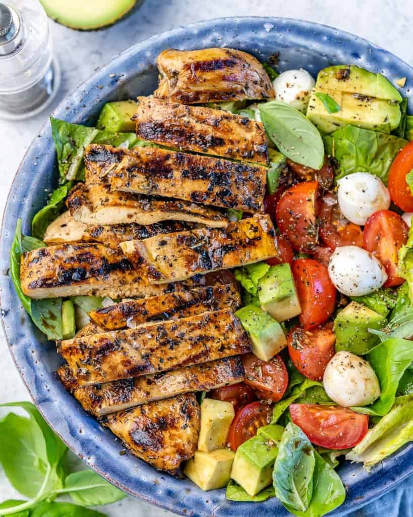 close up view of chicken caprese salad in a blue bowl