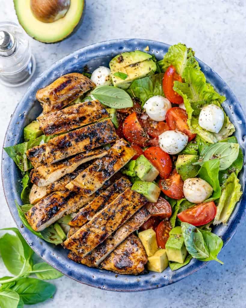 top view of salad in a blue bowl with sliced grilled chicken