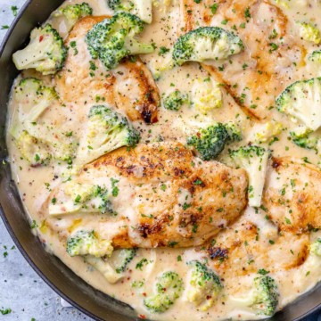 top view creamy chicken breast with broccoli in a black skillet