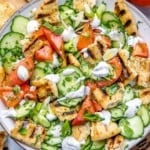 top view chopped salad with naan bread and creamy dressing on a white plate