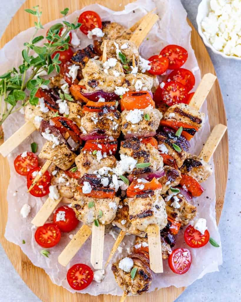 top view chicken kabobs garnished with feta cheese, herbs, and tomatoes 