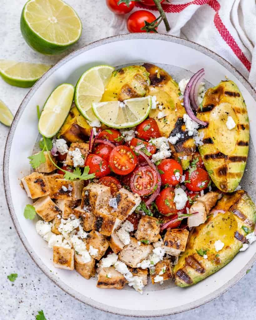 top view of chicken and avocado salad with limes and onion