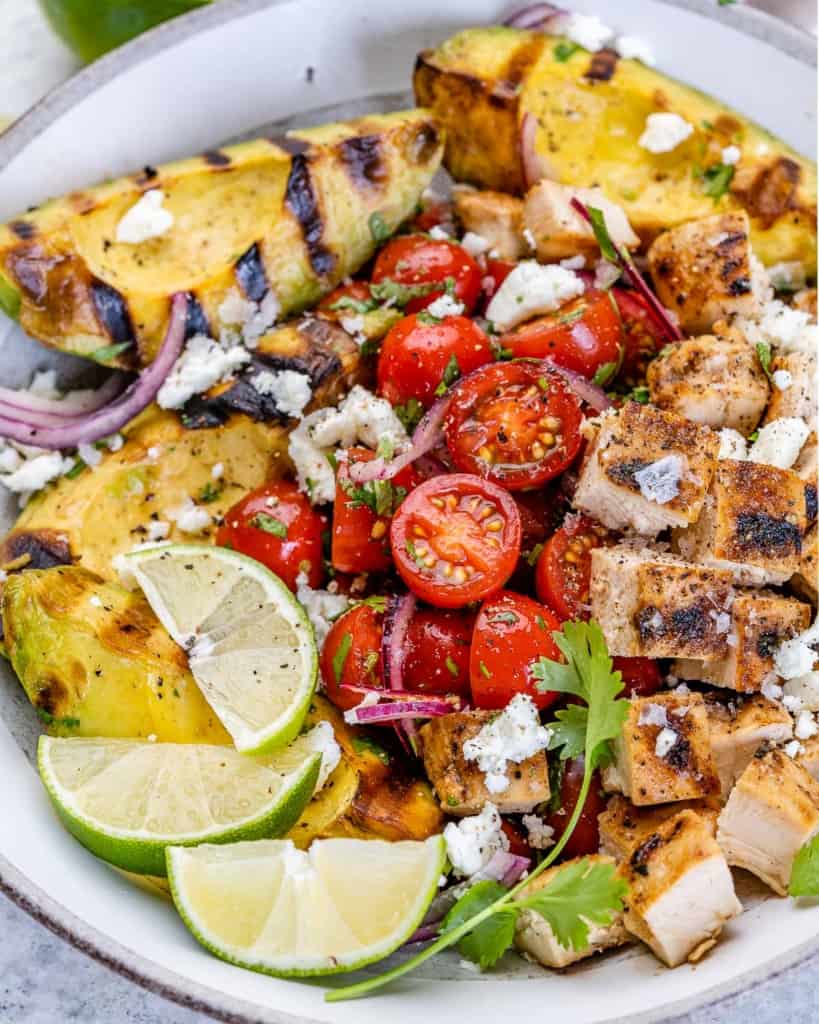 one bowl of grilled avocado chicken salad with tomatoes and feta cheese