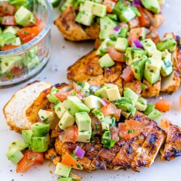 side shot of sliced grilled chicken topped with avocado salsa