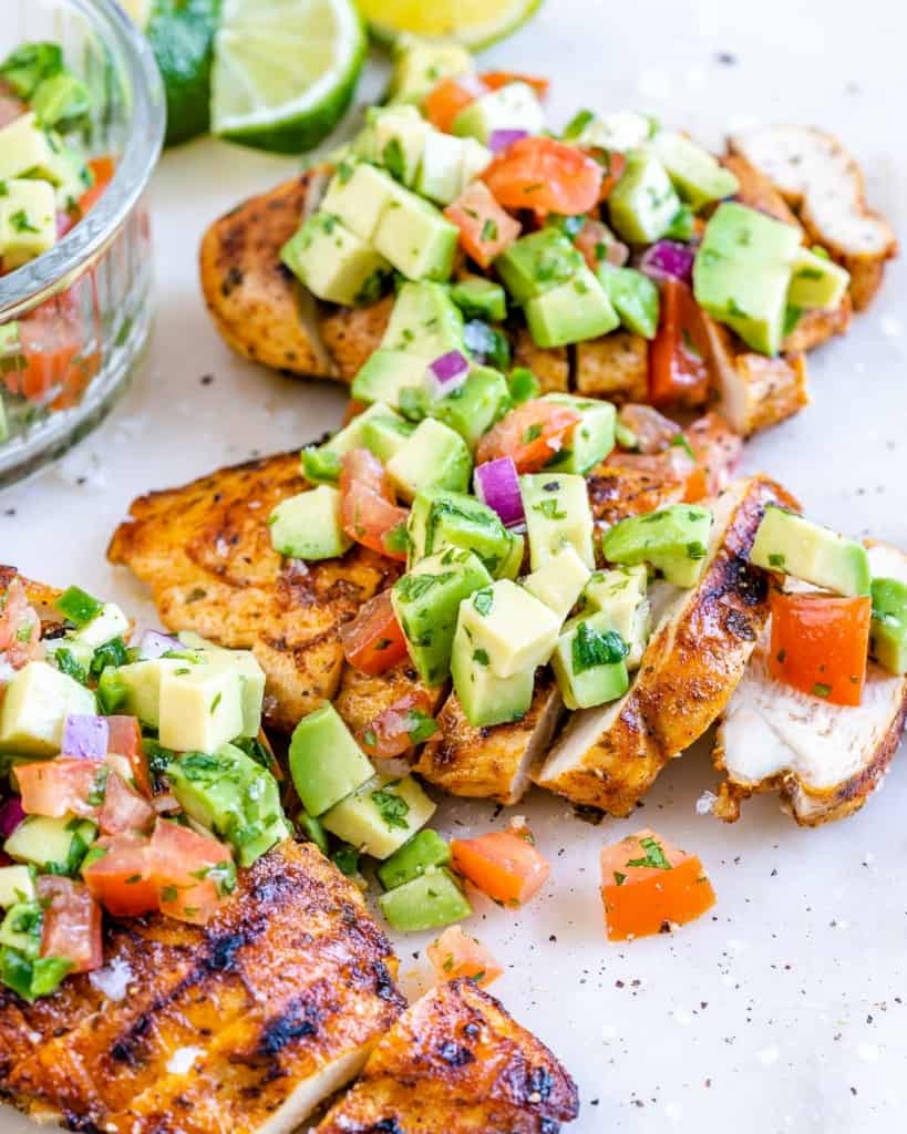 side shot of sliced chicken breast topped with avocado salsa 