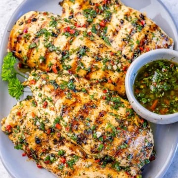 top view of grilled chimichurri chicken breast on a white plate