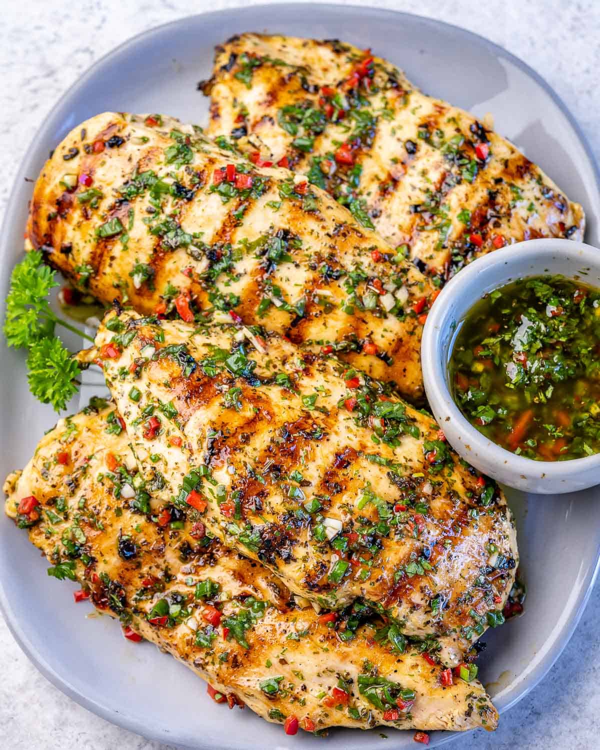 top view of grilled chimichurri chicken breast on a white plate