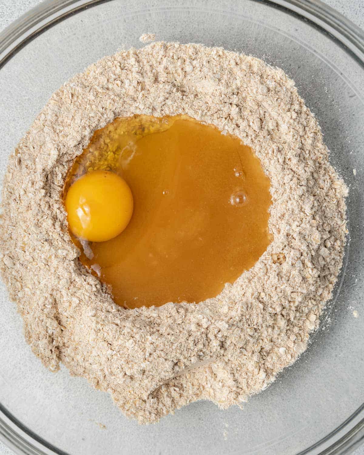 egg, oil, vanilla, and honey added over the dry flour mixture in a bowl.