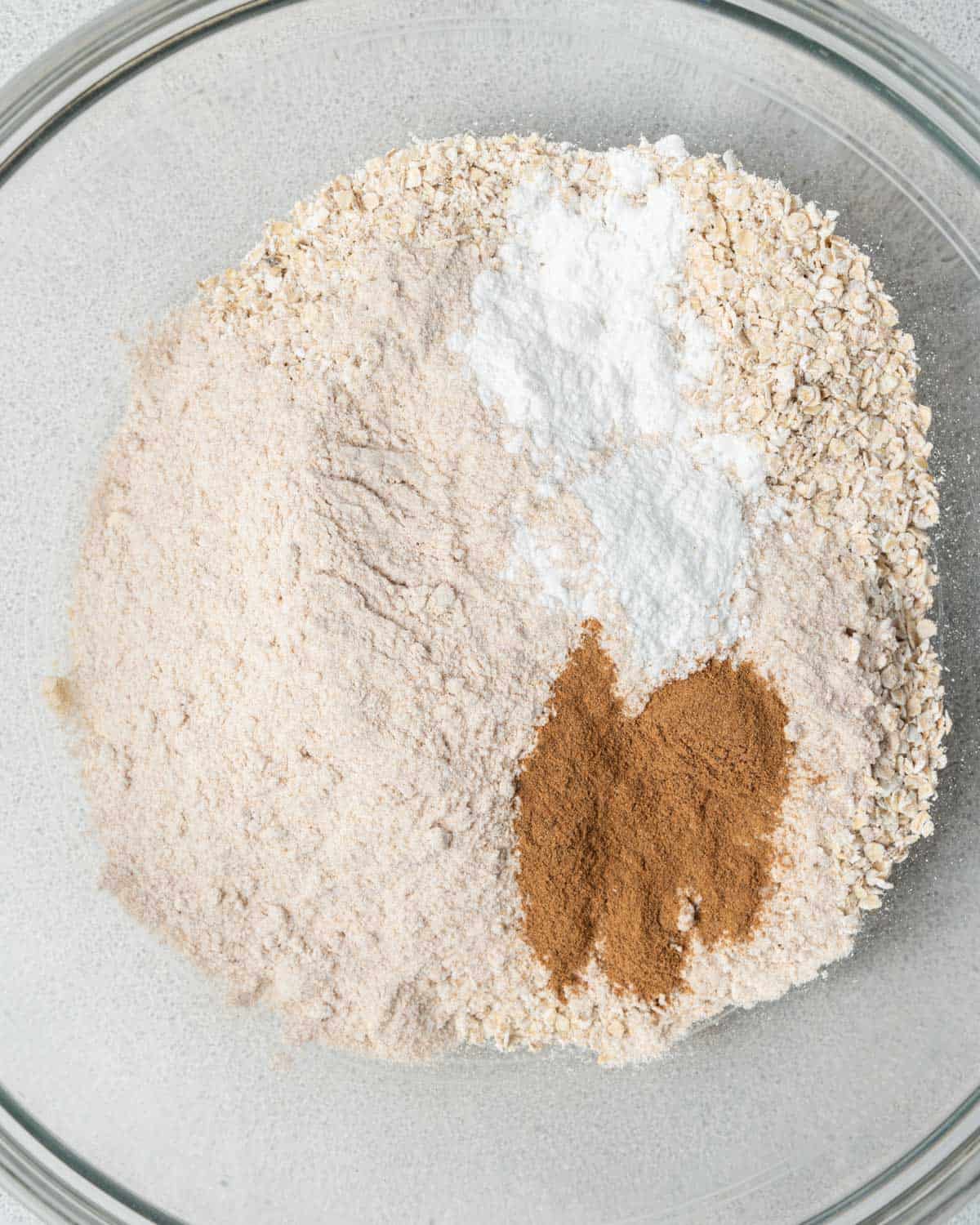 flour, baking powder, protein powder, and cinnamon added to a bowl.