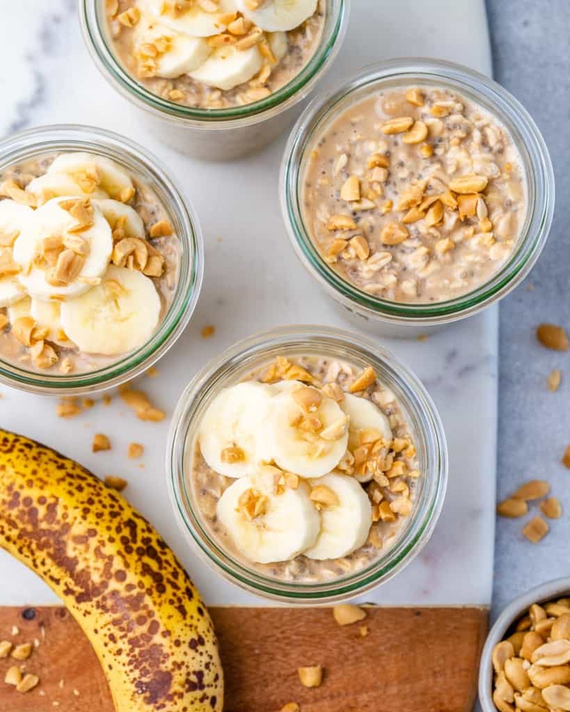 top view of peanut butter overnight oats in jars with bananas and peanuts