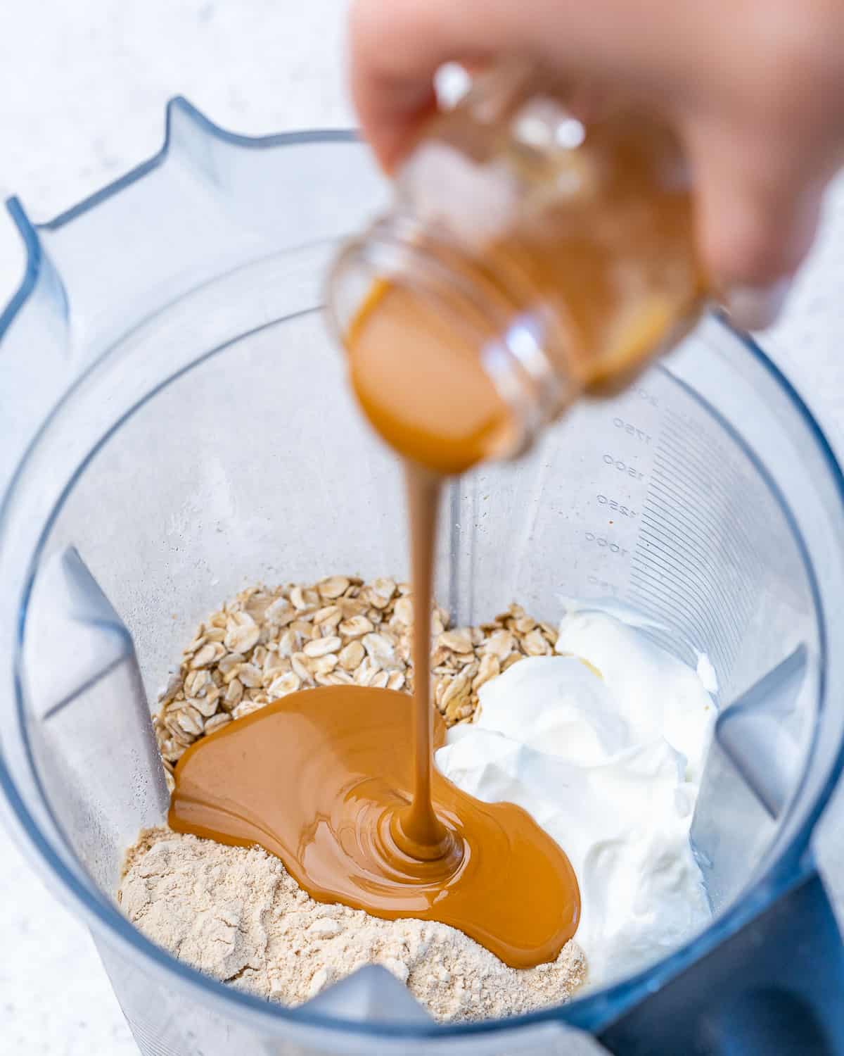 ingredients to make overnight oats with peanut butter being poured into the blender