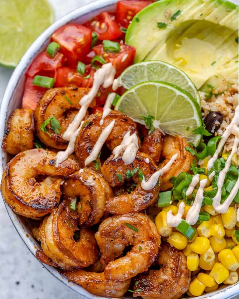 top view of a shrimp burrito bowl with corn, avocado and tomatoes