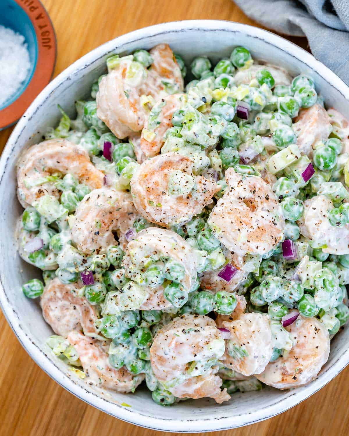 top view creamy shrimp salad with peas and celery in a white bowl