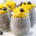side shot of chia pudding in a jar, topped with chopped mango and blueberry