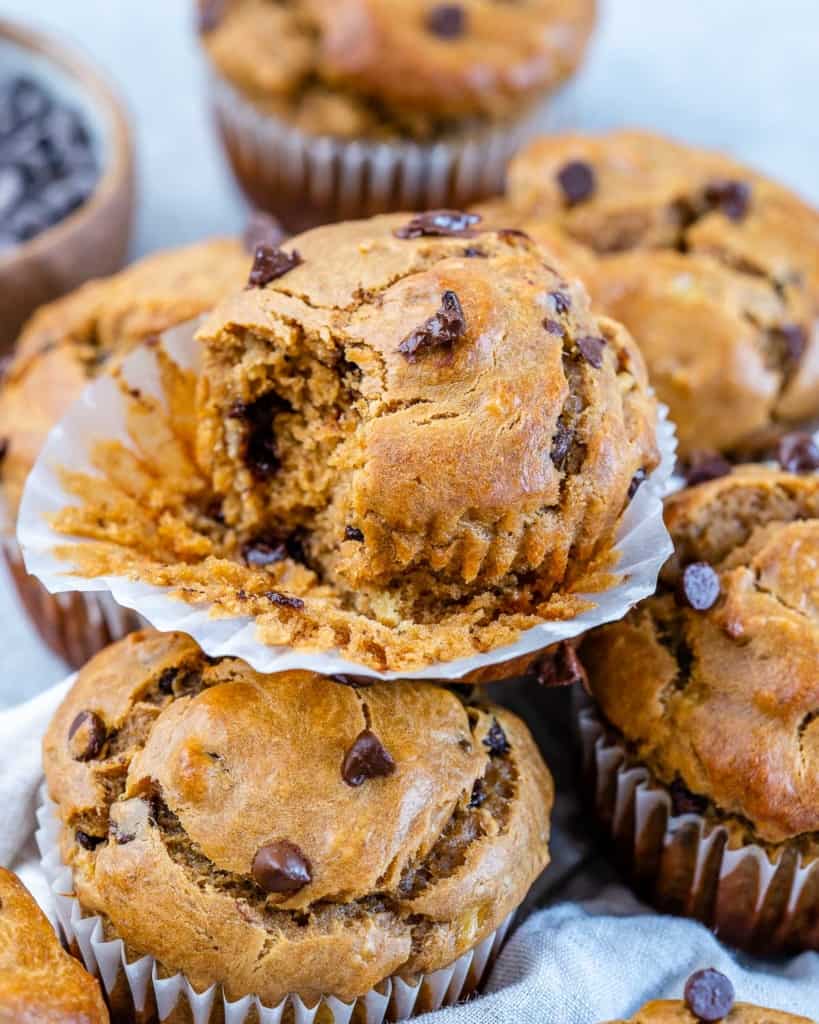 side shot of banana muffins sitting ontop of each other with a bite taken off one muffin