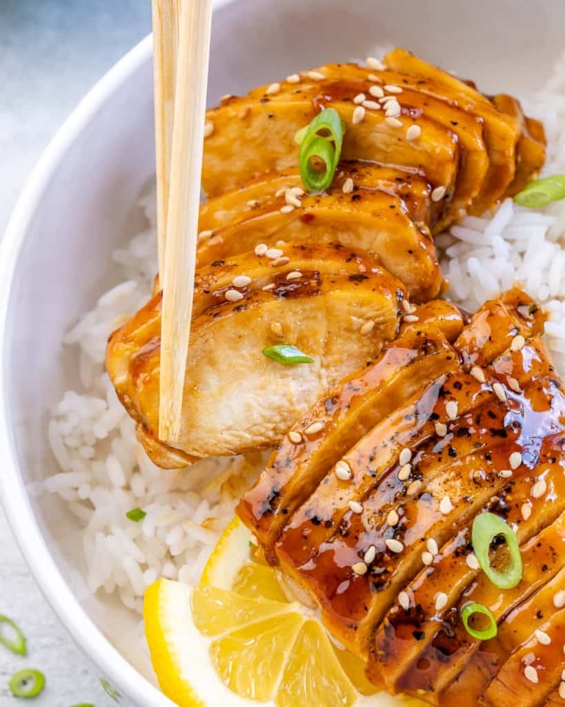 chop sticks holding a piece of sliced chicken