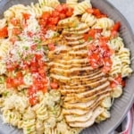 top view of pasta bowl with sliced cajun chicken breast, garnished with tomatoes and parmesan
