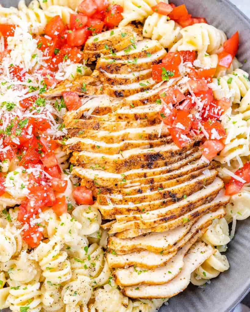 close up sliced cajun chicken over creamy pasta 