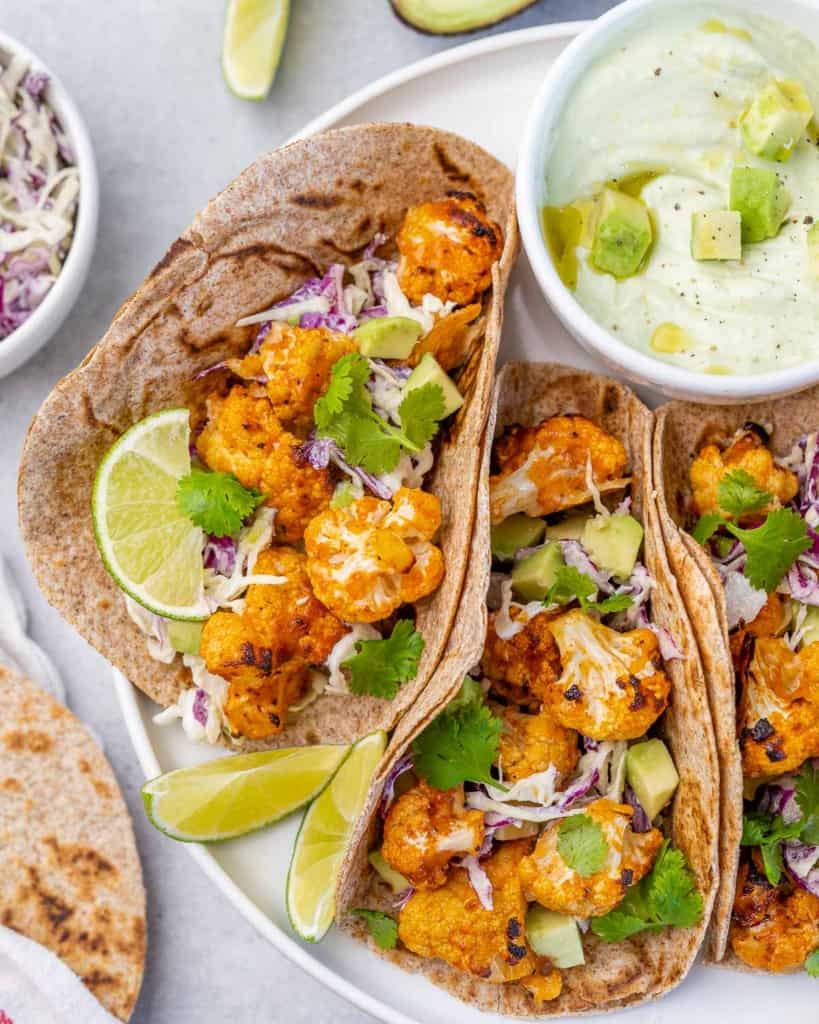 side shot of cauliflower taco with side of yogurt dip on a plate 