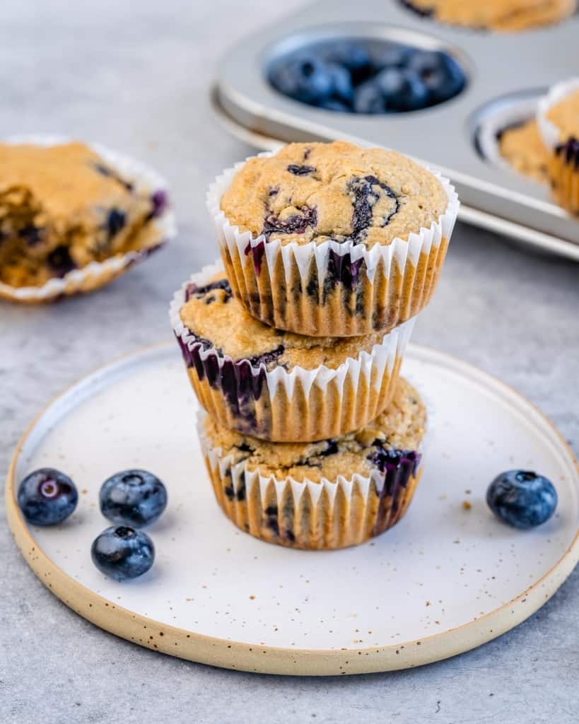 side short of 3 blueberry muffins stacked on each other on a white plate 