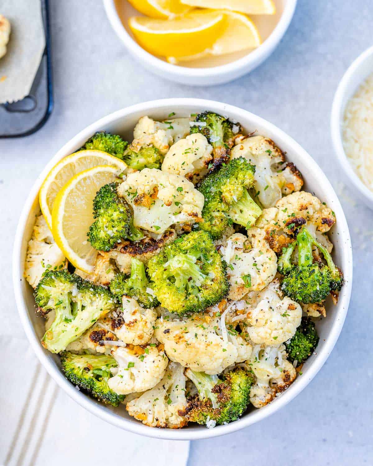 top view of cauliflower and broccoli in bowl with lemon and parsley