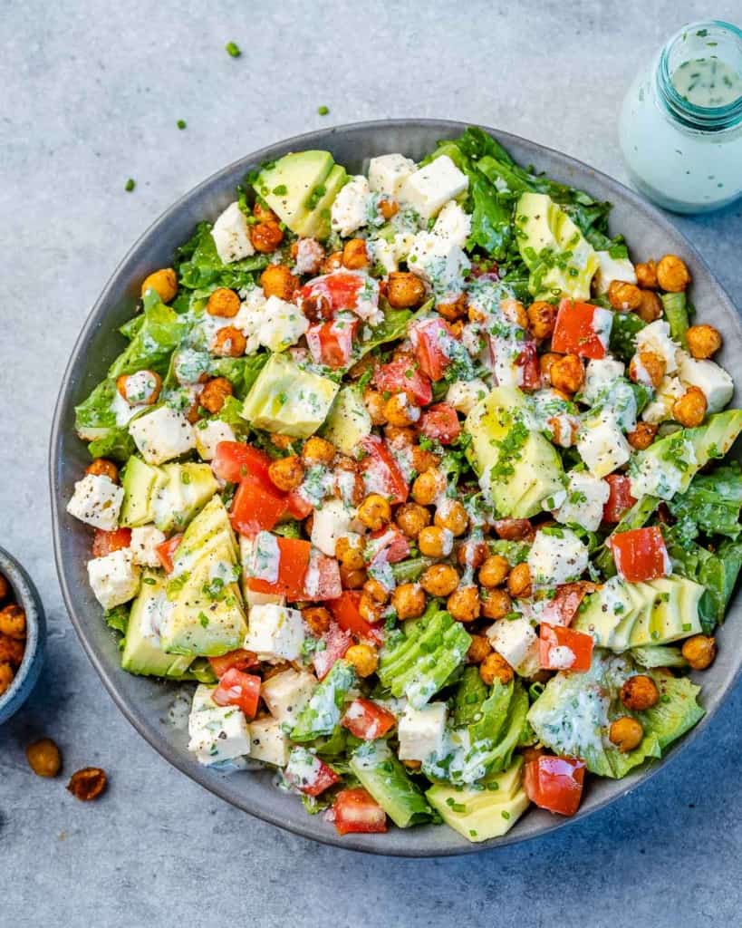top view chickpea salad in a gray bowl topped with avocado and homemade yogurt dressing