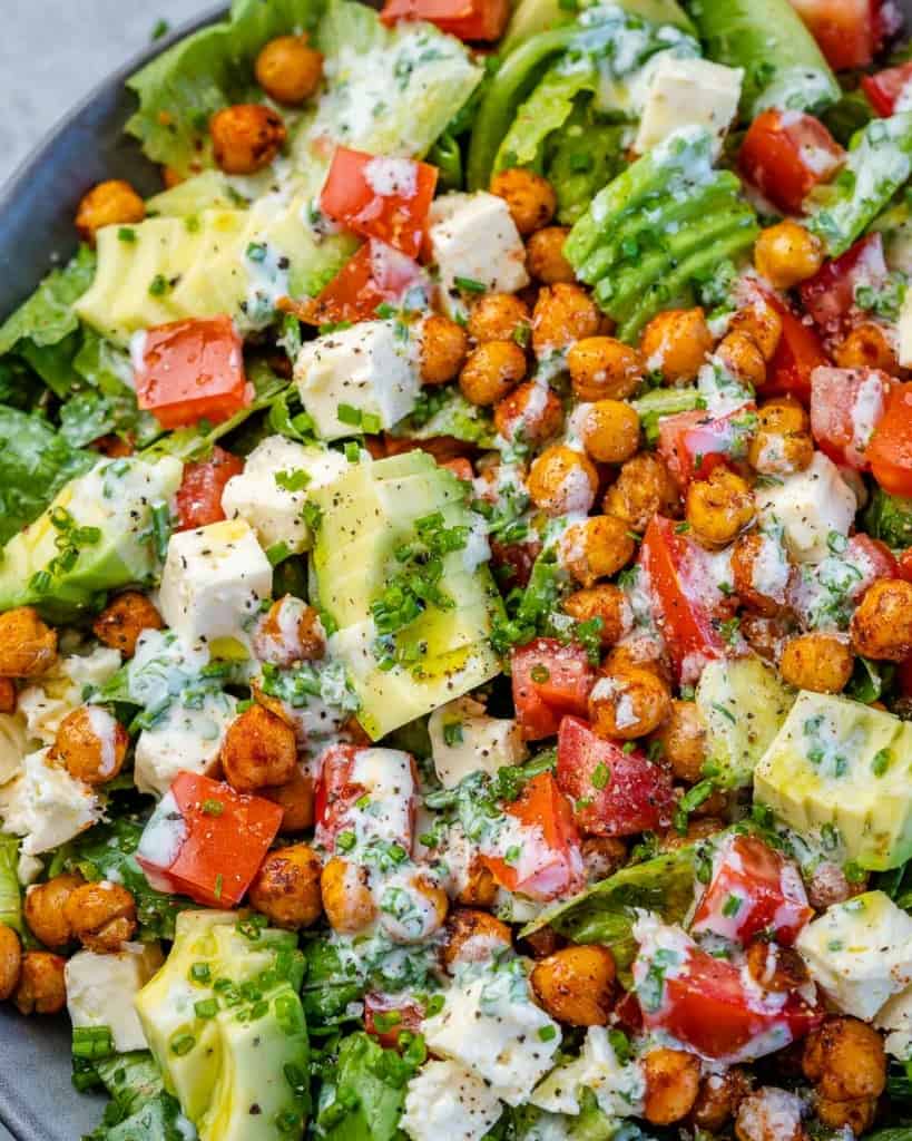 close up chickpea salad with dressing, feta cheese, and avocados