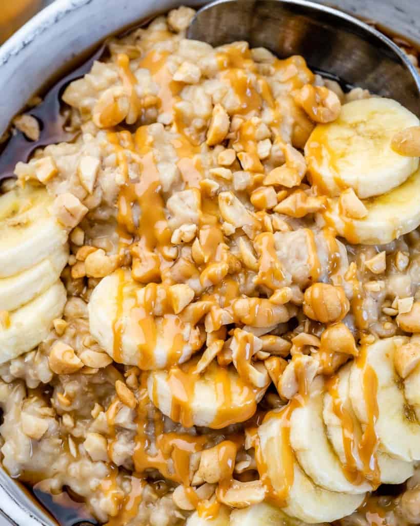 close up steel cut oat bowl. with bananas and peanut butter drizzle.