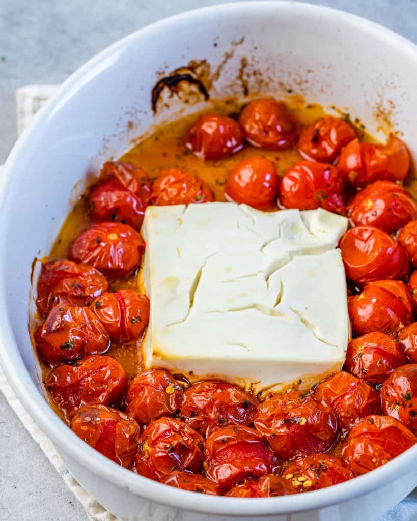baked feta with tomatoes in a white dish after being removed from oven