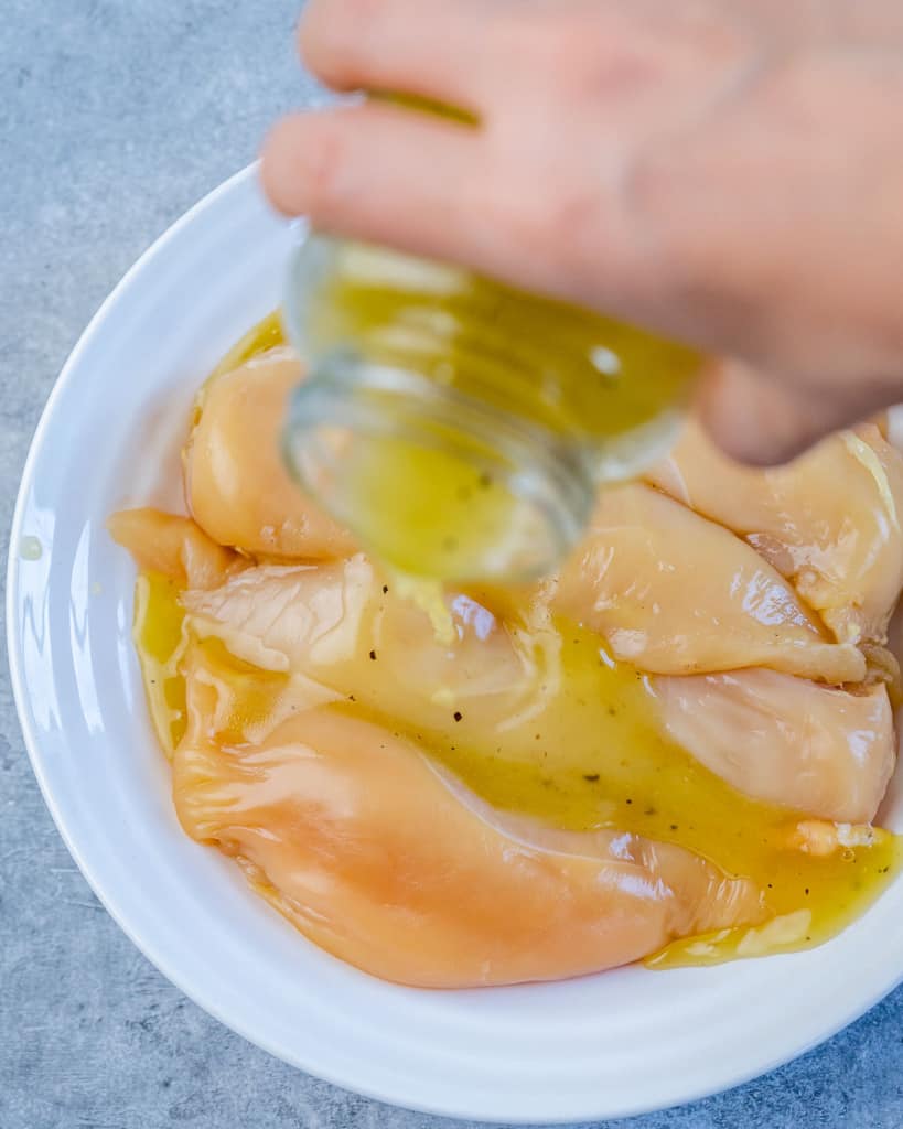 marinade being poured over chicken breast
