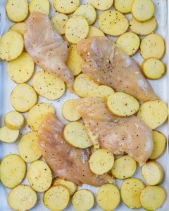 potatoes with raw chicken breast on a sheet pan before baking