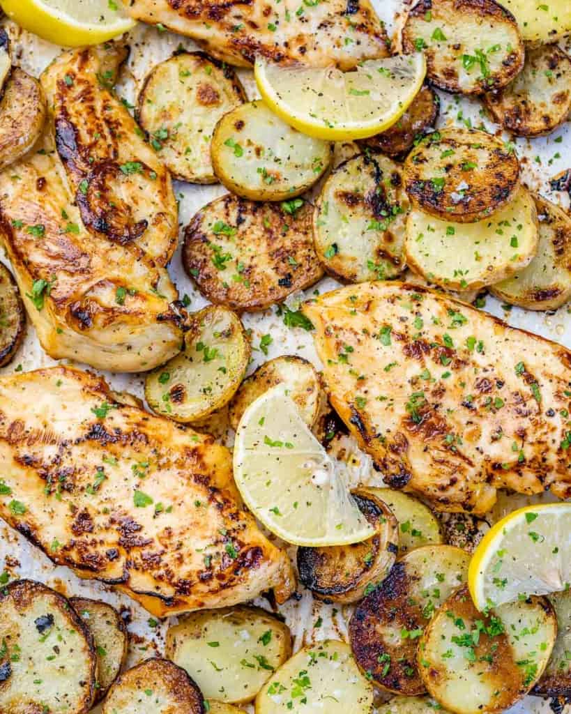 close up baked chicken breast with sliced baby potatoes on a sheet pan