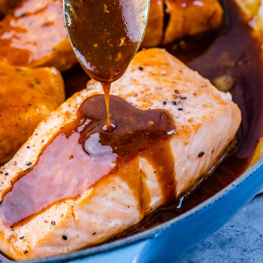 honey sauce being poured over salmon filet