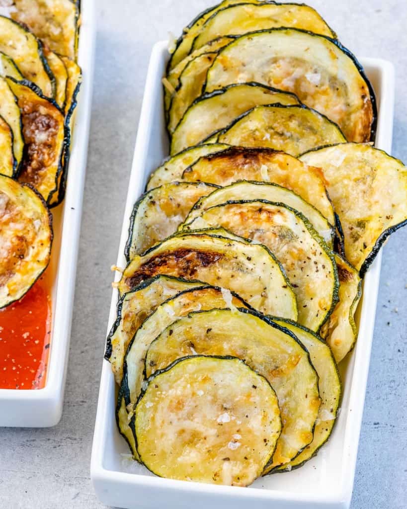 top view of zucchini chips line up in a white dish 