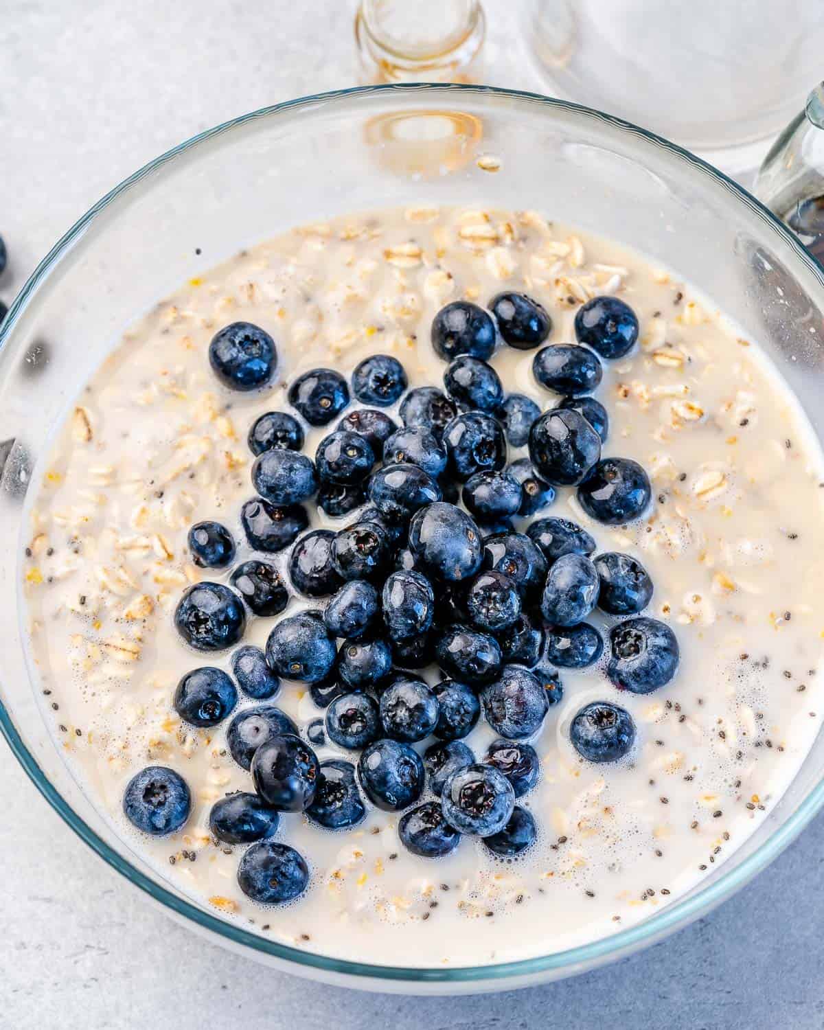 one bowl filled with oats, milk, chia seeds, flax seeds, and blueberries