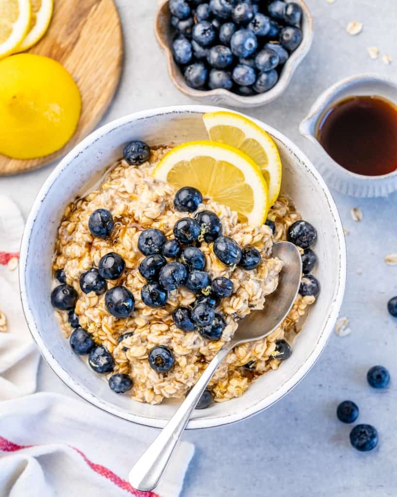 one bowl with blueberries and lemon wedges on top of blueberry overnight oatmeal