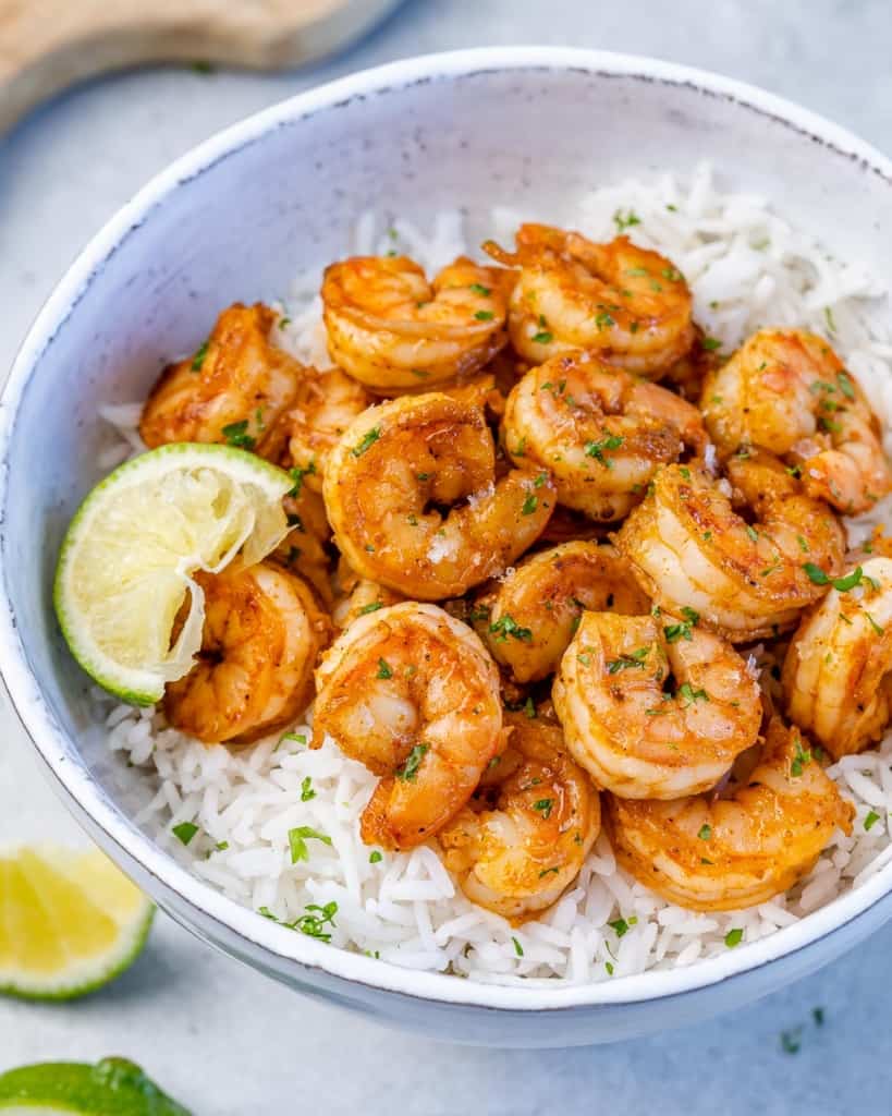 side shot of cajun shrimp over  bowl of white rice