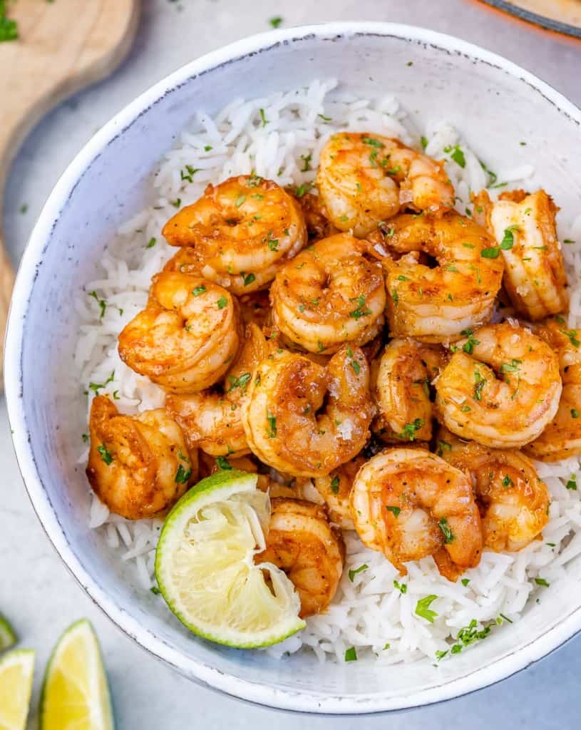 top view of cajun shrimp over a rice of white bowl with a lime wedge for garnish