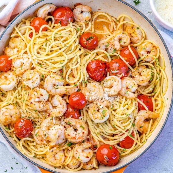 top view spaghetti with tomatoes and shrimp in an orange skillet