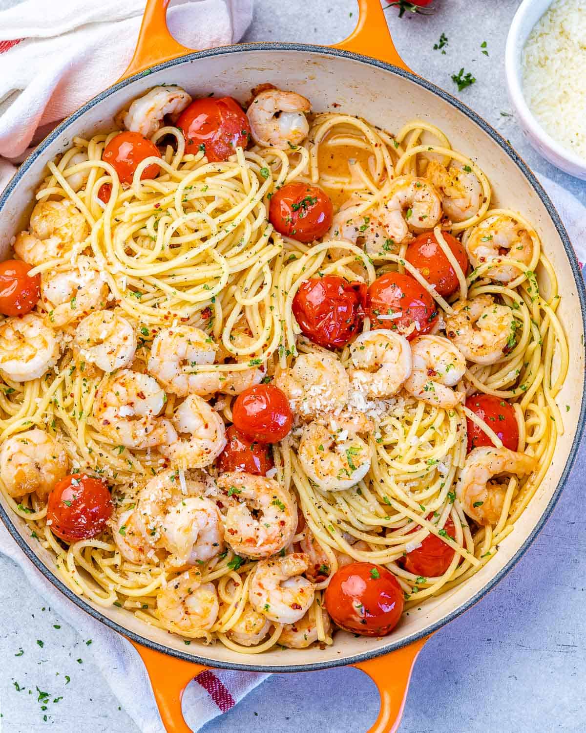 top view spaghetti with tomatoes and shrimp in an orange skillet