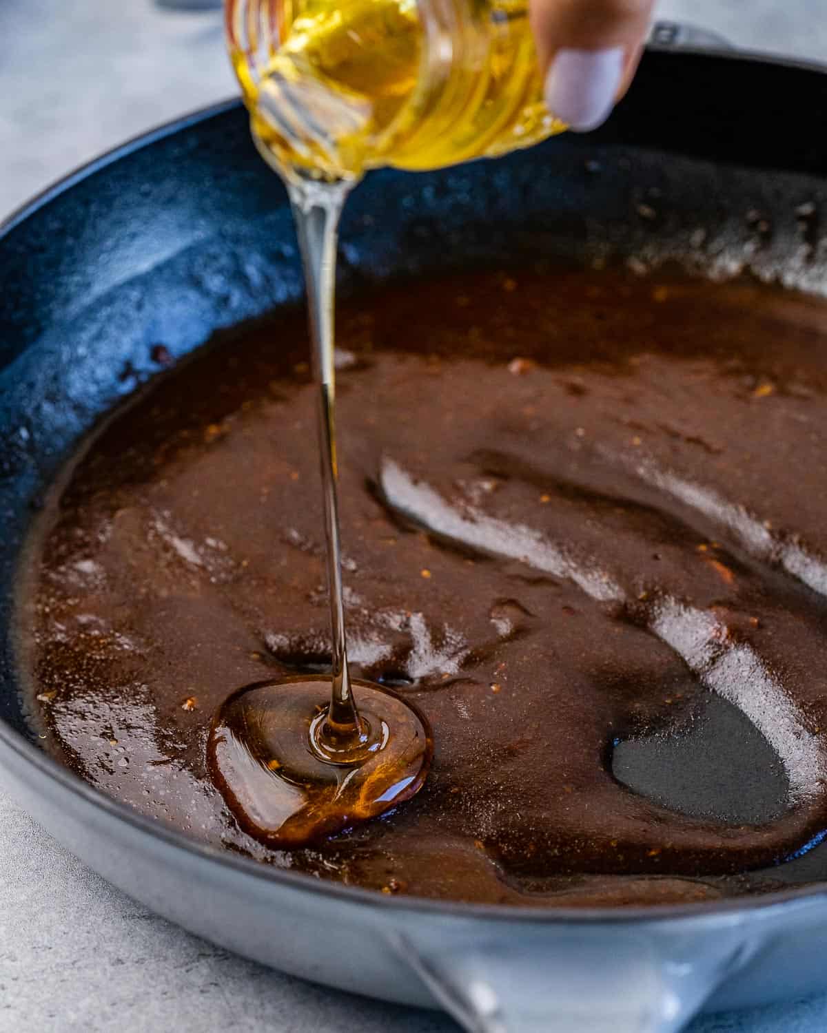 honey is added to make the sauce in a black skillet.