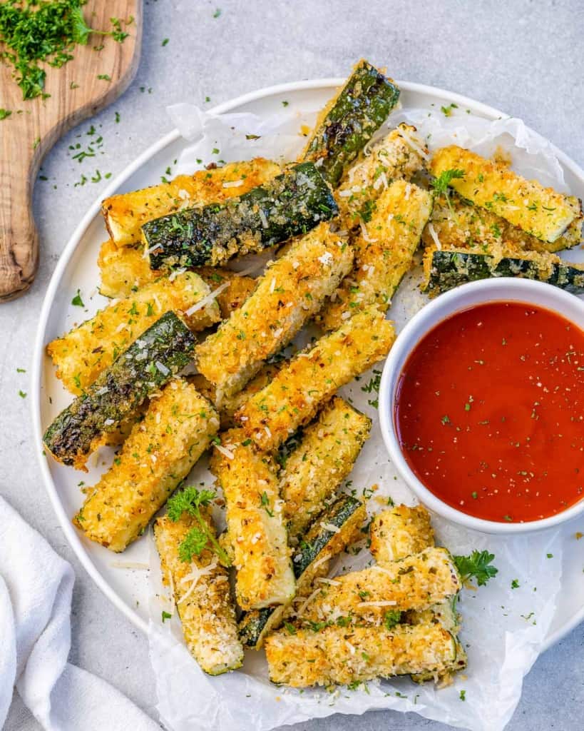 top view of zucchini fries on a plate with dipping red sauce