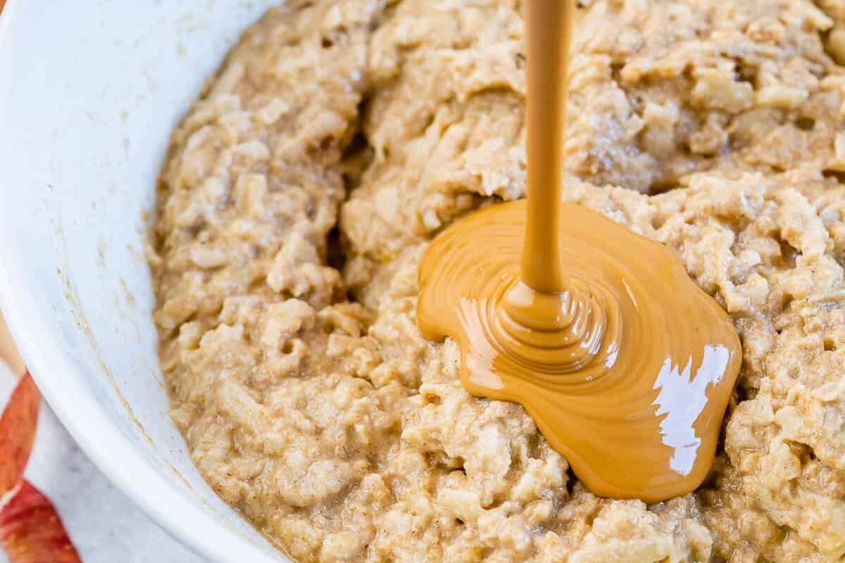 pouring melted peanut butter over the batter in a bowl.