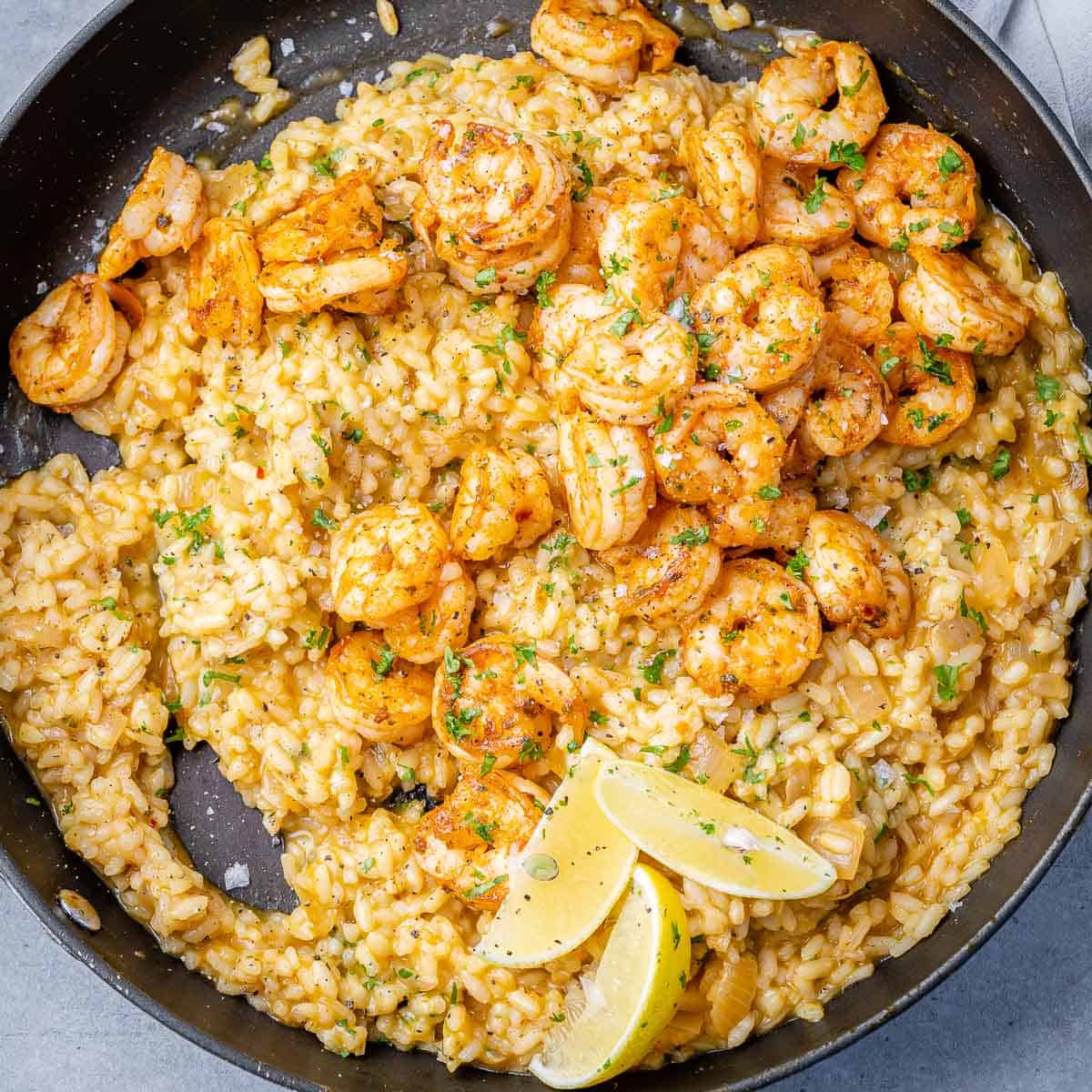 top view risotto in black skillet topped with shrimp