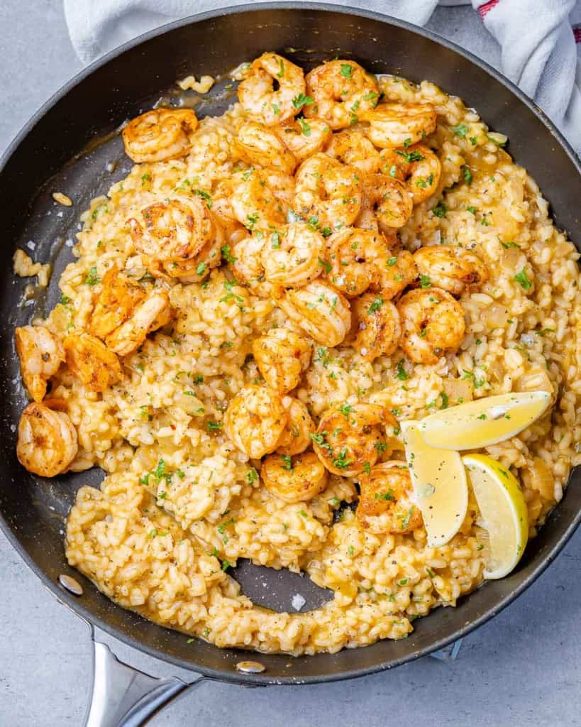 top view risotto topped with shrimp with lemon granishes