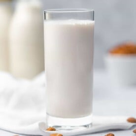 square image of a clear glass cup cup filled with almond milk