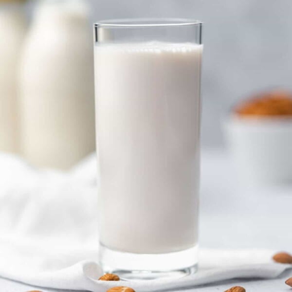 square image of a clear glass cup cup filled with almond milk