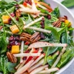 white bowl with apple pecan salad with cranberries and vinagirette