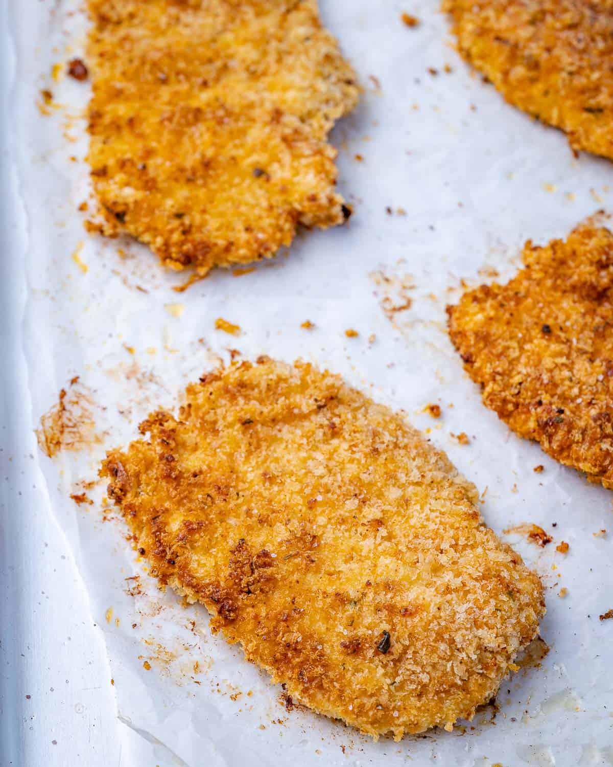 chicken cutlets on baking sheet with breadcrumb coating